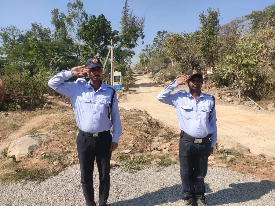 Two security guards saluting at an industrial site